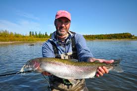 fisherman in river holding a large rainbow fish