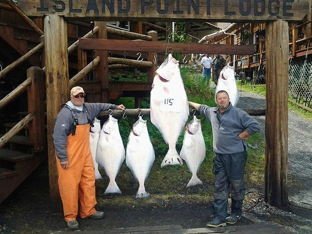 Guests and fishing guide posing with large halibut