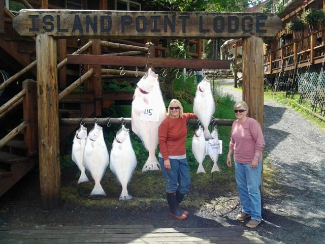 two women standing with several halibut