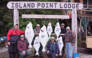 Men standing with hanging halibut