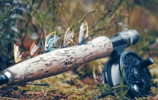 A fly rod and reel combo, decorated with an assortment of flies, rests at the ready.