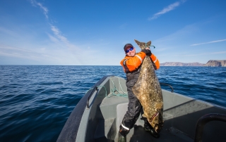 A proud angler displays his bounty while halibut fishing in Alaska.
