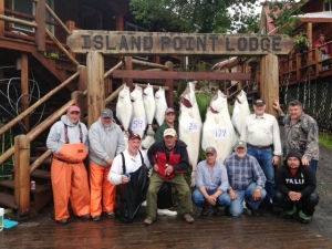 A group of men sitting in front of a large haul of halibut caught on an Alaska fishing trip.